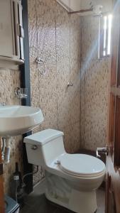 y baño con aseo y lavamanos. en Hostal Casa Cultural Mindo en Mindo