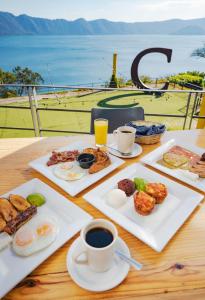 a table with plates of food and a cup of coffee at Cardedeu Hotel Lago de Coatepeque in El Congo