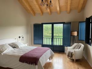 a bedroom with a bed and a chair and windows at Grandes Duplex nuevos con Jardin - 3 llaves, Los Gayoles Rural in Castropol