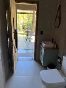 a bathroom with a toilet and a door to a patio at Recanto Tereza Dias in Lagoinha