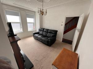 a living room with a black leather couch and a television at Spacious 3bed house in Southend-on-Sea