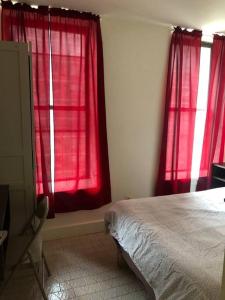 sypialnia z czerwonymi zasłonami, łóżkiem i biurkiem w obiekcie 1C CLOSe w Nowym Jorku