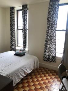 a bedroom with a bed and two windows with curtains at 1C CLOSe in New York