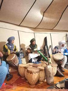 a group of people sitting in a tent with drums at Jardin Kotori Luxury Camp in Merzouga
