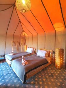 a bedroom with two beds in a tent at Jardin Kotori Luxury Camp in Merzouga