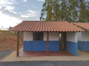 una pequeña casa azul y blanca con techo rojo en Chalés relíquia canastra, en São Roque de Minas