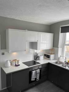 a kitchen with white cabinets and a stove top oven at Studio Apartment In Brighton & Hove in Brighton & Hove