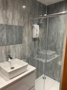 a bathroom with a sink and a glass shower at Chandlers Country House in Rothesay