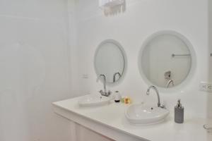 Baño blanco con 2 lavabos y 2 espejos en Hotel Miconia, en Puerto Baquerizo Moreno
