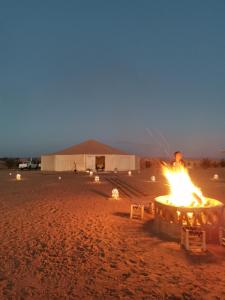 a fire pit in the middle of a desert at night at Jardin Kotori Luxury Camp in Merzouga