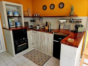 eine Küche mit orangefarbenen Wänden und Arbeitsplatten aus Holz in der Unterkunft o'Filao in Grand-Bourg