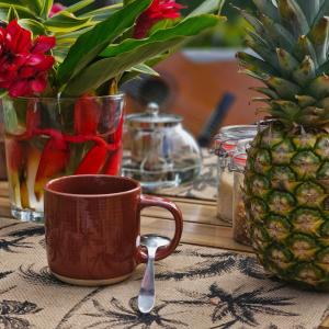 eine Kaffeetasse und ein Löffel auf einem Tisch mit einer Ananas in der Unterkunft o'Filao in Grand-Bourg + 9 Fotos