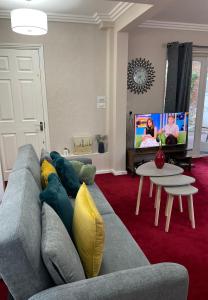 ein Wohnzimmer mit einem Sofa und einem TV in der Unterkunft Luxurious and Elegant Homestay in Kent in Wrotham