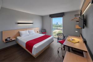Cette chambre comprend un lit, un bureau et une fenêtre. dans l'établissement City Express by Marriott Reynosa Aeropuerto, à Reynosa