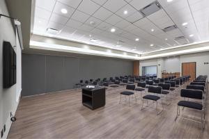 uma sala de conferências com cadeiras, um pódio e um ecrã em City Express by Marriott Reynosa Aeropuerto em Reynosa