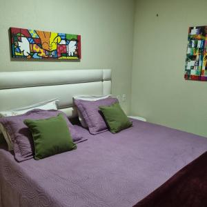 a bedroom with a bed with purple sheets and pillows at Apartamento Dei Fiori in Guaramiranga