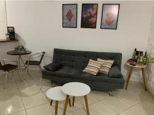 sala de estar con sofá negro y 2 mesas en Apartamento confortável com espaço exclusivo, en Cachoeira Paulista