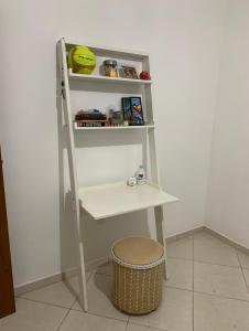 Un escritorio blanco con un estante y un taburete. en Apartamento confortável com espaço exclusivo, en Cachoeira Paulista
