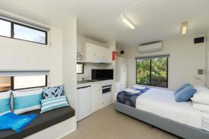 a bedroom with a large bed and a kitchen at Reflections Nambucca Heads - Holiday Park in Nambucca Heads