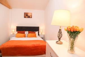 1 dormitorio con 1 cama y un jarrón de tulipanes naranjas en Unique 1 bed Flat Near Heathrow en Hillingdon