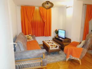 uma sala de estar com cortinas cor de laranja e uma televisão em Family Apartment em Kumanovo