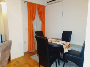 uma mesa de jantar com cadeiras e uma cortina laranja em Family Apartment em Kumanovo