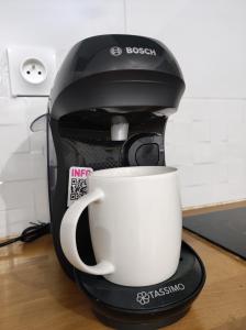 a coffee maker with a white cup on a counter at Paris cosy private room with shared space - Chambre privée avec espace commun Paris in Vitry-sur-Seine