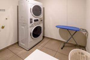 uma máquina de lavar e secar roupa num quarto com um banco azul em City Express Junior by Marriott Bogota Aeropuerto em Bogotá