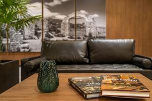 - une table basse avec un canapé en cuir et des livres dans l'établissement City Express Plus by Marriott San Luis Potosi, à San Luis Potosí