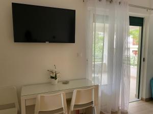 a dining room with a table and a television on the wall at Studio Promajna 2592a in Promajna
