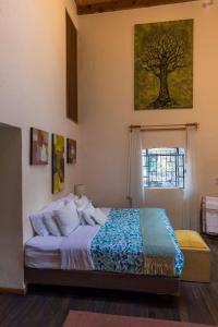 a bedroom with a bed with a tree painting on the wall at Meztli: Casa Boutique & Spa in Mexico City