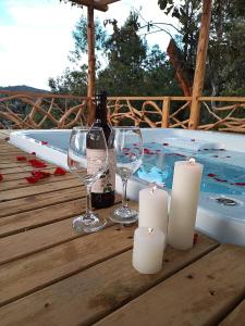 una mesa con copas de vino y velas junto a una bañera de hidromasaje en Guayacan Alojamiento, en Santa Elena