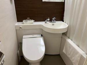 La petite salle de bains est pourvue de toilettes et d'un lavabo. dans l'établissement Hotel Shinjukuya, à Machida