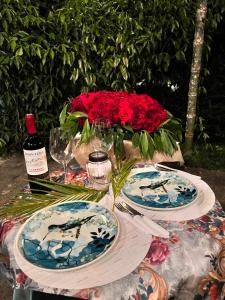 a table with plates and a vase of red roses at Natural Luxury Birding Lodge - Premium Birdwatching near Cali in Papagalleros