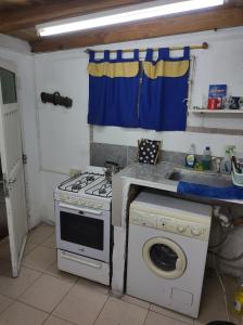 a kitchen with a stove and a washing machine at Amanecer campestre junto al Ceibo. in Burzaco