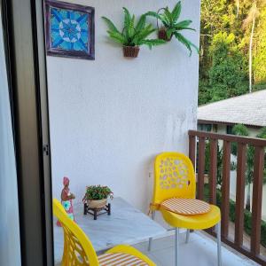 a patio with yellow chairs and a table and a plant at Apartamento Dei Fiori in Guaramiranga