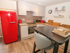 einen roten Kühlschrank in einer Küche mit einem Tisch in der Unterkunft Riverside Cottage in Amlwch