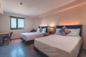 Una habitación de hotel con dos camas y un escritorio. en Lyz Business Hotel Piura, en Piura