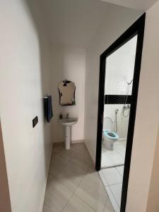 La salle de bains est pourvue de toilettes, d'un lavabo et d'un miroir. dans l'établissement Résidence Talhaoui, à Saïdia