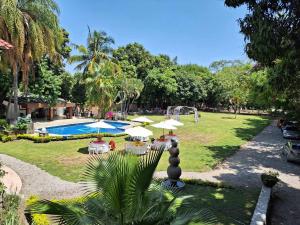 a park with tables and umbrellas and a pool at Casa De La O Yautepec in Yautepec de Zaragoza