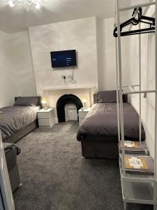 a bedroom with two beds and a tv on the wall at Juz Apartments Manchester airport in Altrincham