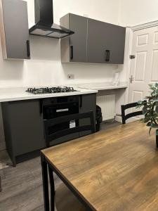 a kitchen with a stove and a wooden table at Juz Apartments Manchester airport in Altrincham