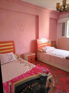 1 dormitorio con 2 camas en una habitación con paredes rosas en شقه فاخره للايجار بكامب شيزار, en Alejandría