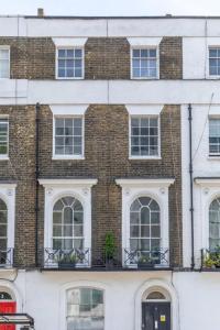 a large brick building with white windows and potted plants at Incredibly Located Studio Flat - Camden Town in London