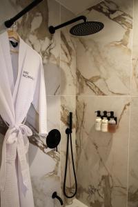 uma casa de banho com um chuveiro e um roupão branco na parede em MrNomad Boutique Hotel Parisian Townhouse em Dallas