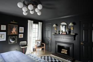 a bedroom with black walls and a fireplace at MrNomad Boutique Hotel Parisian Townhouse in Dallas