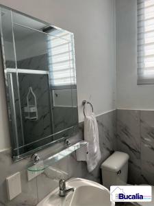 y baño con lavabo, espejo y aseo. en Bucalia House Machala, en Machala