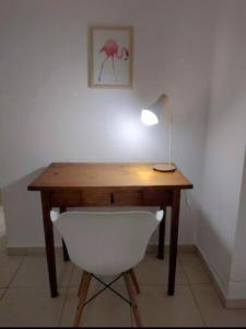 einen Schreibtisch mit einer Lampe und einem weißen Stuhl in der Unterkunft BeelApt - Departamento elegante y seguro, con Cochera Exclusiva in La Plata