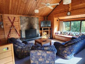 a living room with couches and a large fireplace in a cabin at Dakune Chill - The Lodge in Ohakune