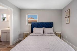 a bedroom with a bed with a blue headboard and a window at Modern getaway near the beach with room for a boat in West Palm Beach